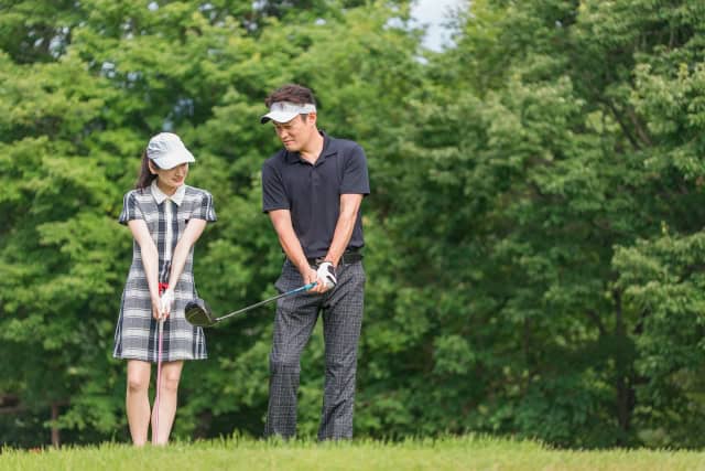 女性にゴルフを教える男性
